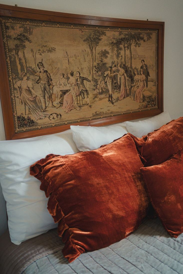 Chambre avec tapisserie ancienne et coussins rouille