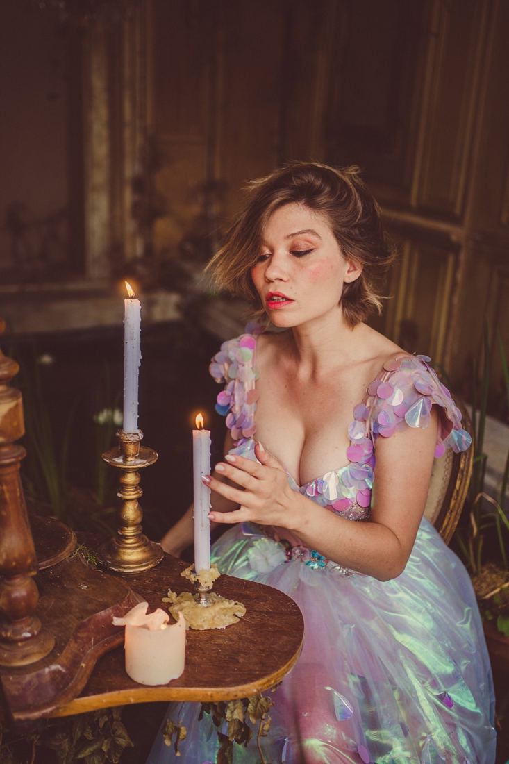 Portrait féérique d’une modèle en robe pastel, bougie à la main, dans un salon du château