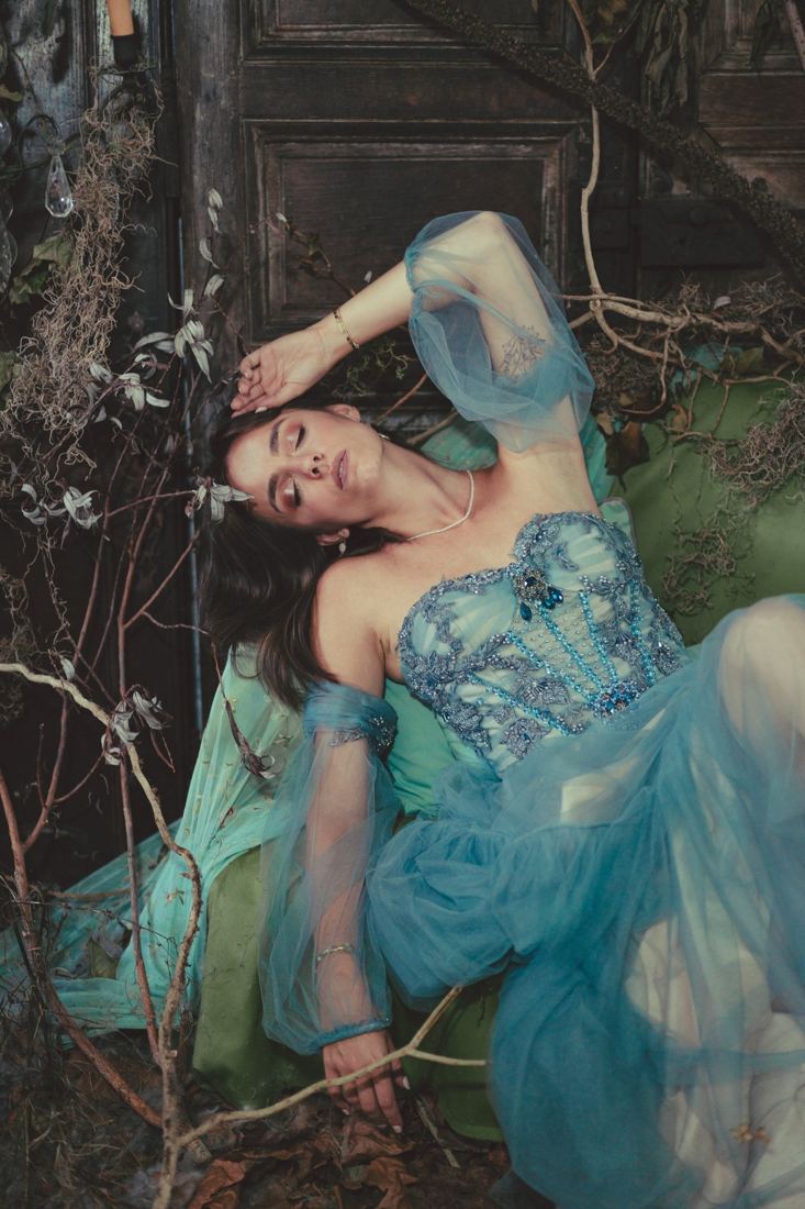 Modèle en robe bleue allongée parmi les branchages